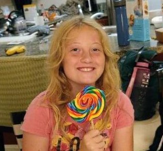 Kara grinning while holding a huge lollipop 