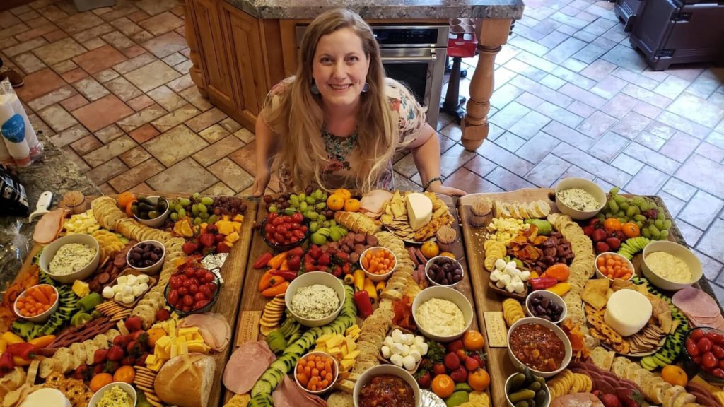 Sheri with three large charcuterie boards laid out by her